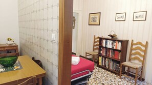 A small room with a bed, a wooden chair, a bookshelf, and a tiled floor. - Apartment Near Biennale Theatre by Ca-sa Check (Venice)