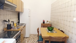 A compact kitchen with a stove, sink, and a dining table with chairs. - Apartment Near Biennale Theatre by Ca-sa Check (Venice)