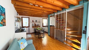 A cozy interior with a wooden ceiling, a dining area with chairs and a table, and a staircase with a railing.