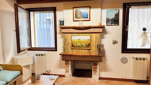 A cozy living room with a fireplace, a sofa, a coffee table, and a radiator. - Di Sole e D'azzurro by Ca-sa Check (Chioggia)