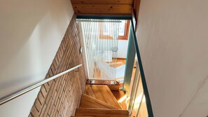 A wooden staircase with a metal handrail, leading to a room with a window and a bed. - Di Sole e D'azzurro by Ca-sa Check (Chioggia)