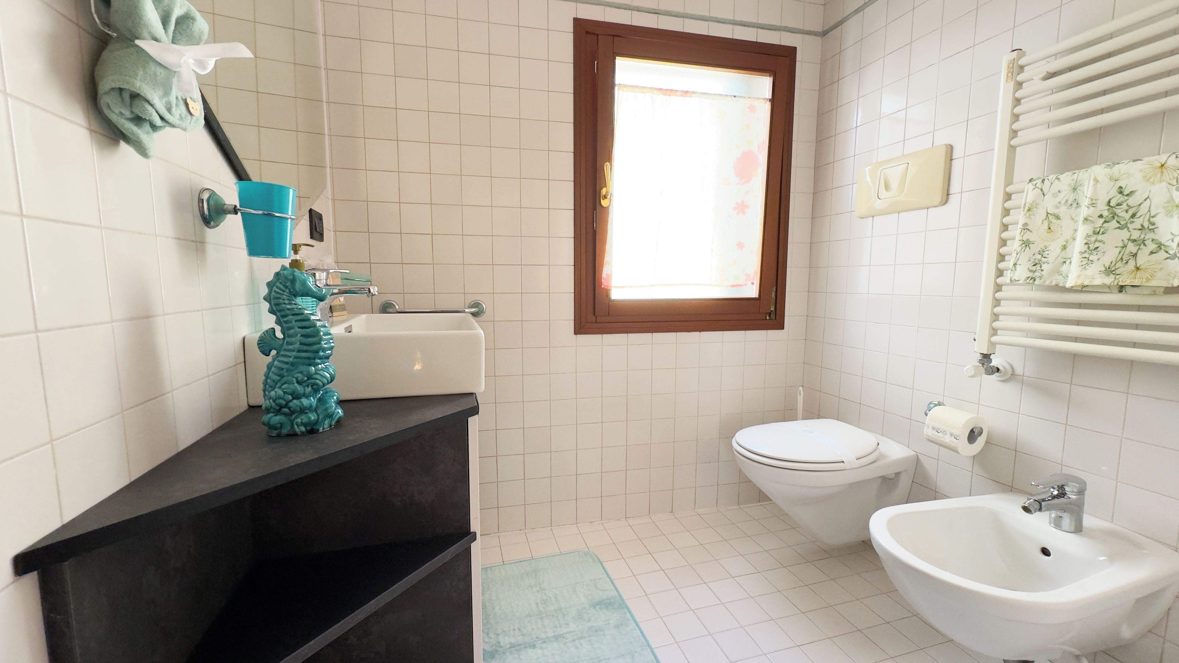 A bathroom with a toilet, sink, and a window.