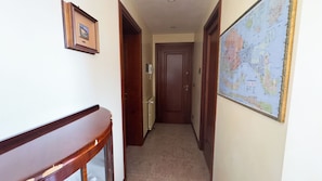 A narrow hallway with a wooden bench on the left, a framed picture on the wall, and a large map on the right. - Appartamento a Cannaregio by Ca-sa Check (Venice)