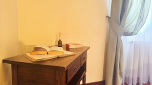 Ein Holztisch mit einem offenen Buch, einer kleinen Flasche und einem Stapel Bücher.