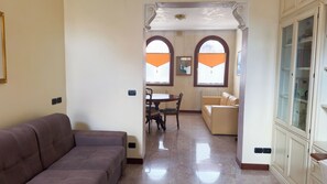 A living room with a sofa, a dining area with a table and chairs, and a kitchen area with cabinets. - Appartamento a Cannaregio by Ca-sa Check (Venice)