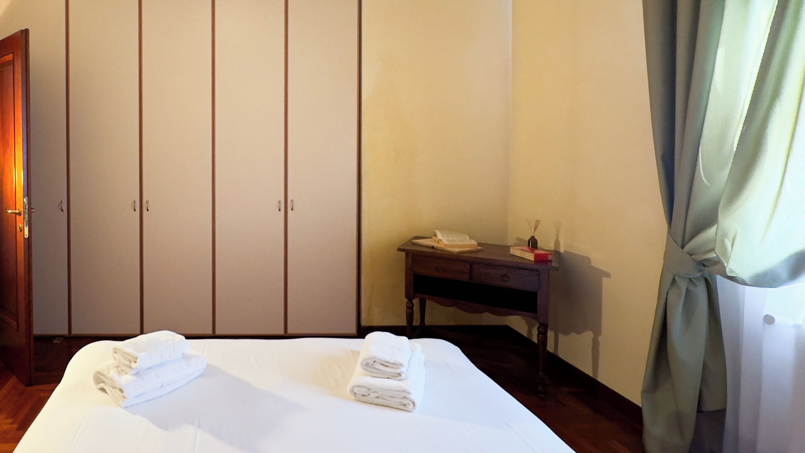 A hotel room with a bed, a desk, and a wardrobe.