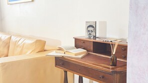 A room with a leather sofa, a wooden desk with a book, a picture frame, and a vase. - Appartamento a Cannaregio by Ca-sa Check (Venice)