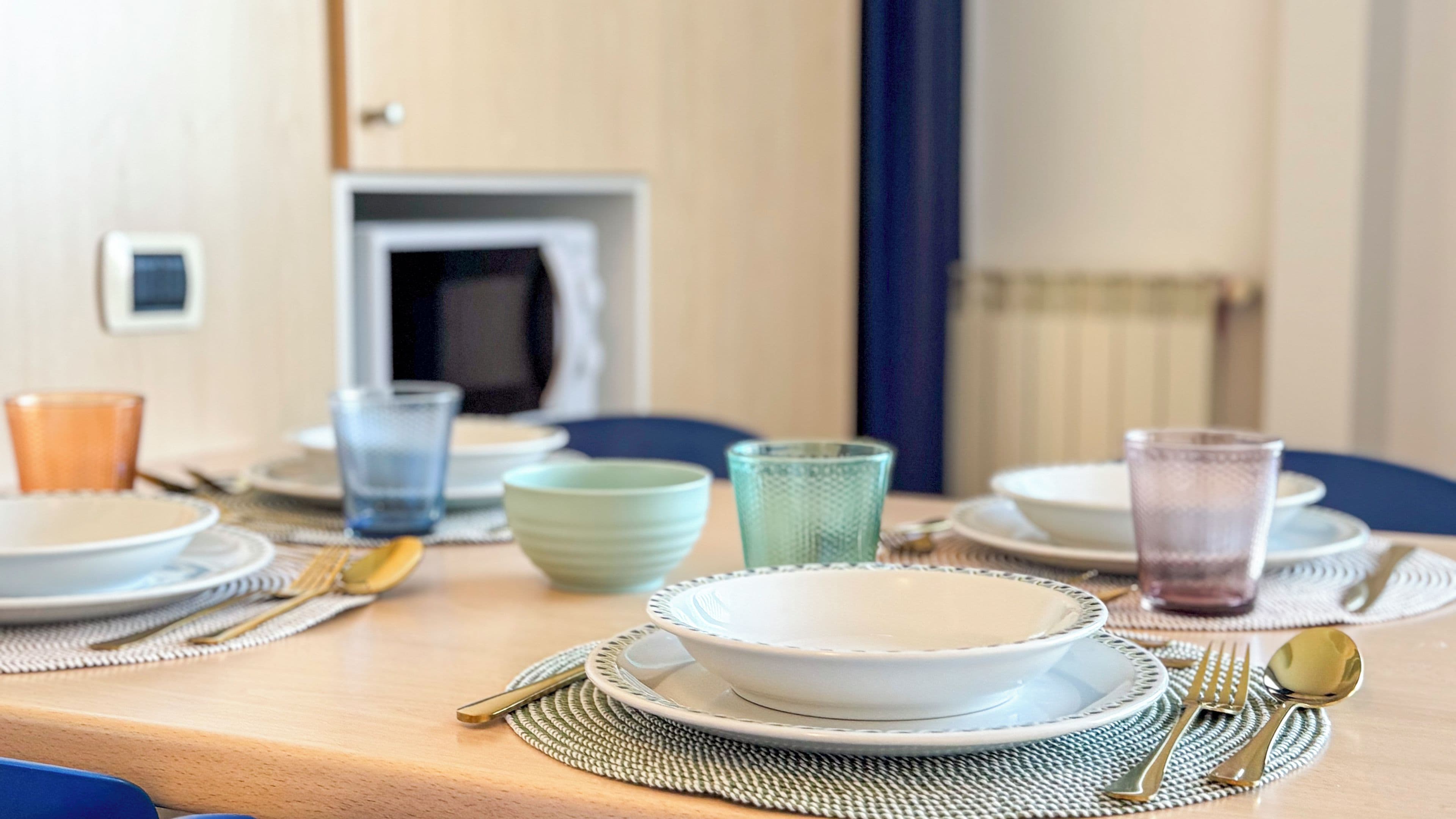 Una mesa de comedor dispuesta con platos, tazones, vasos y cubiertos.