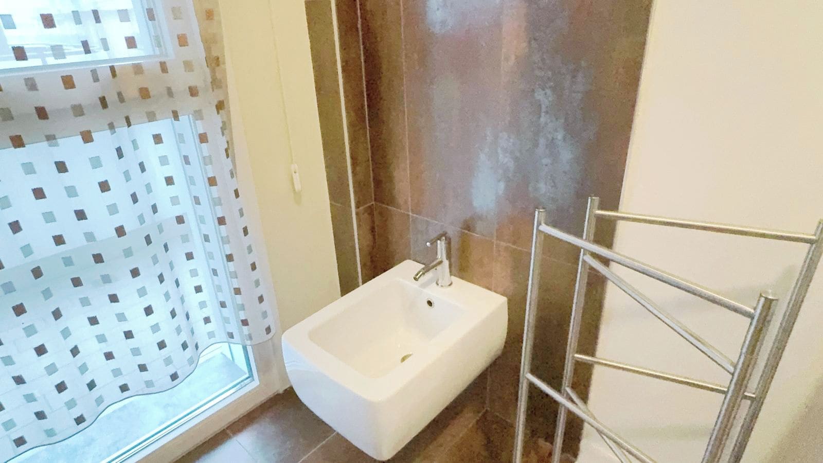 Une salle de bain avec un lavabo blanc, un espace douche et un porte-serviettes.