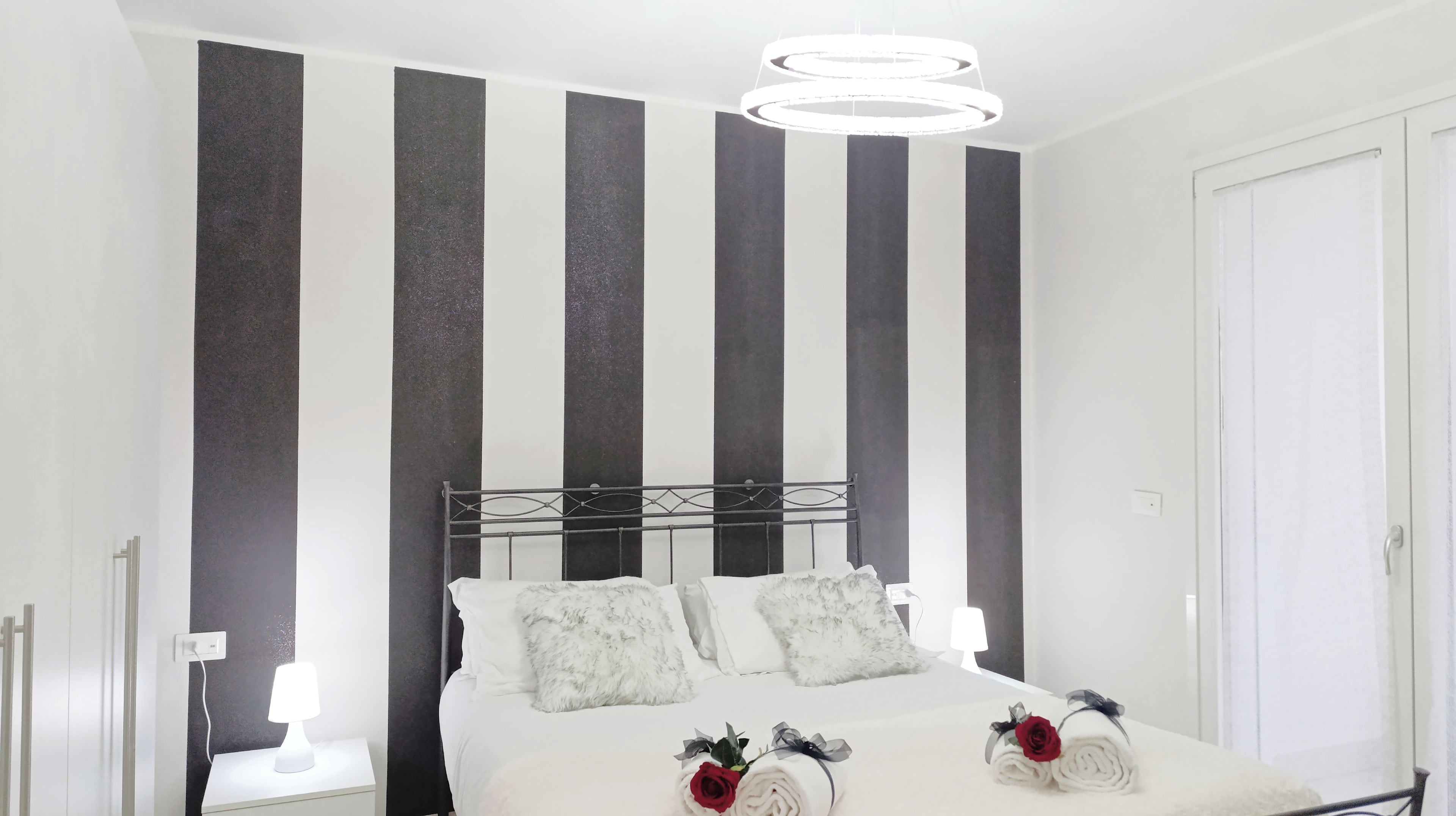 A modern bedroom with a bed, two bedside tables, and a large window.