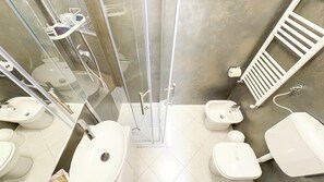 Ein modernes Badezimmer mit einer Glaskabinedusche, zwei Waschbecken, einem Bidet und einer Toilette.