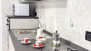 Eine Küche mit Spüle aus Edelstahl, einer Mikrowelle und einer Kaffeemaschine auf der Arbeitsfläche.