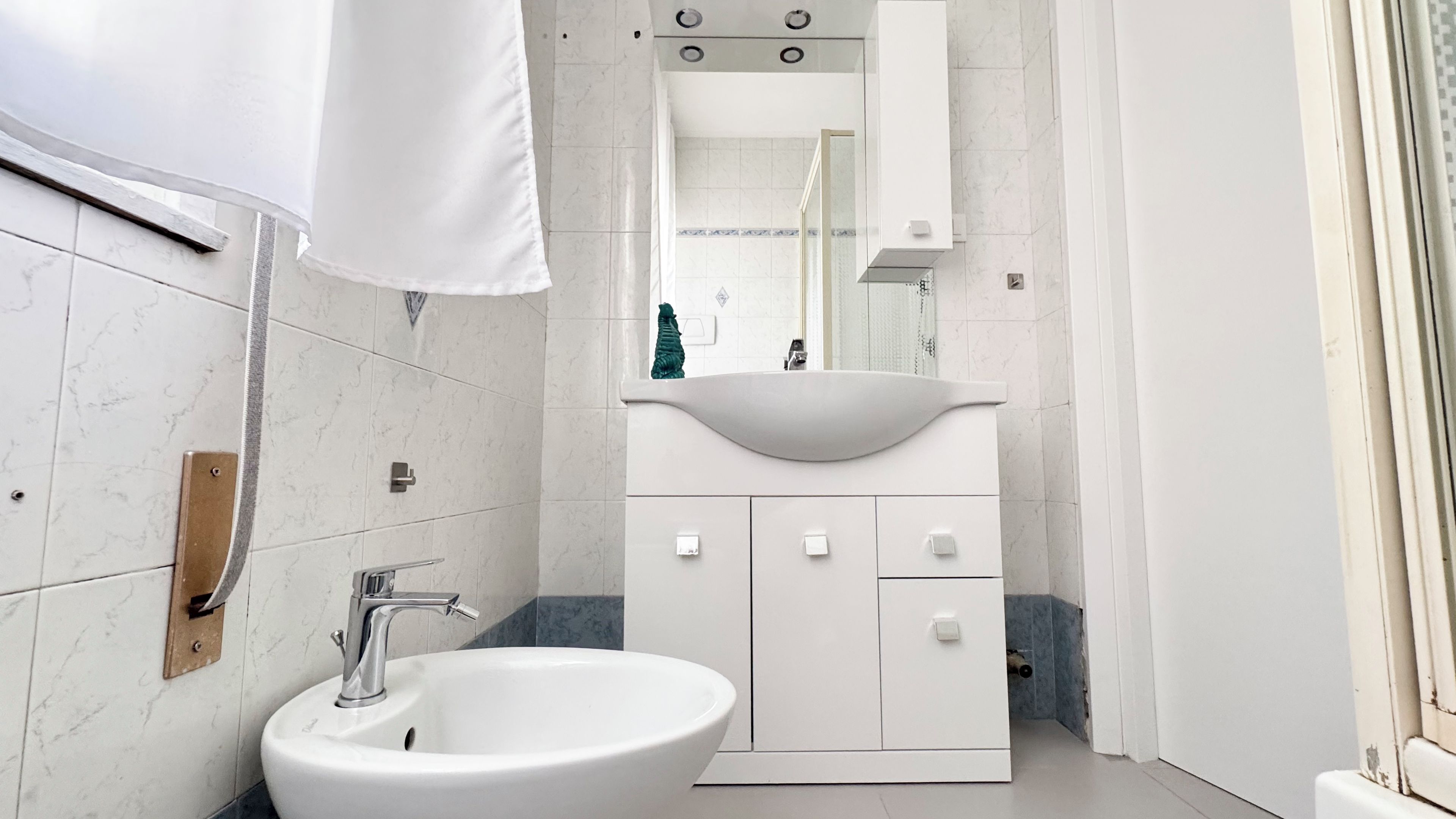 A modern bathroom with a white sink, a mirror above it, and a cabinet with drawers.