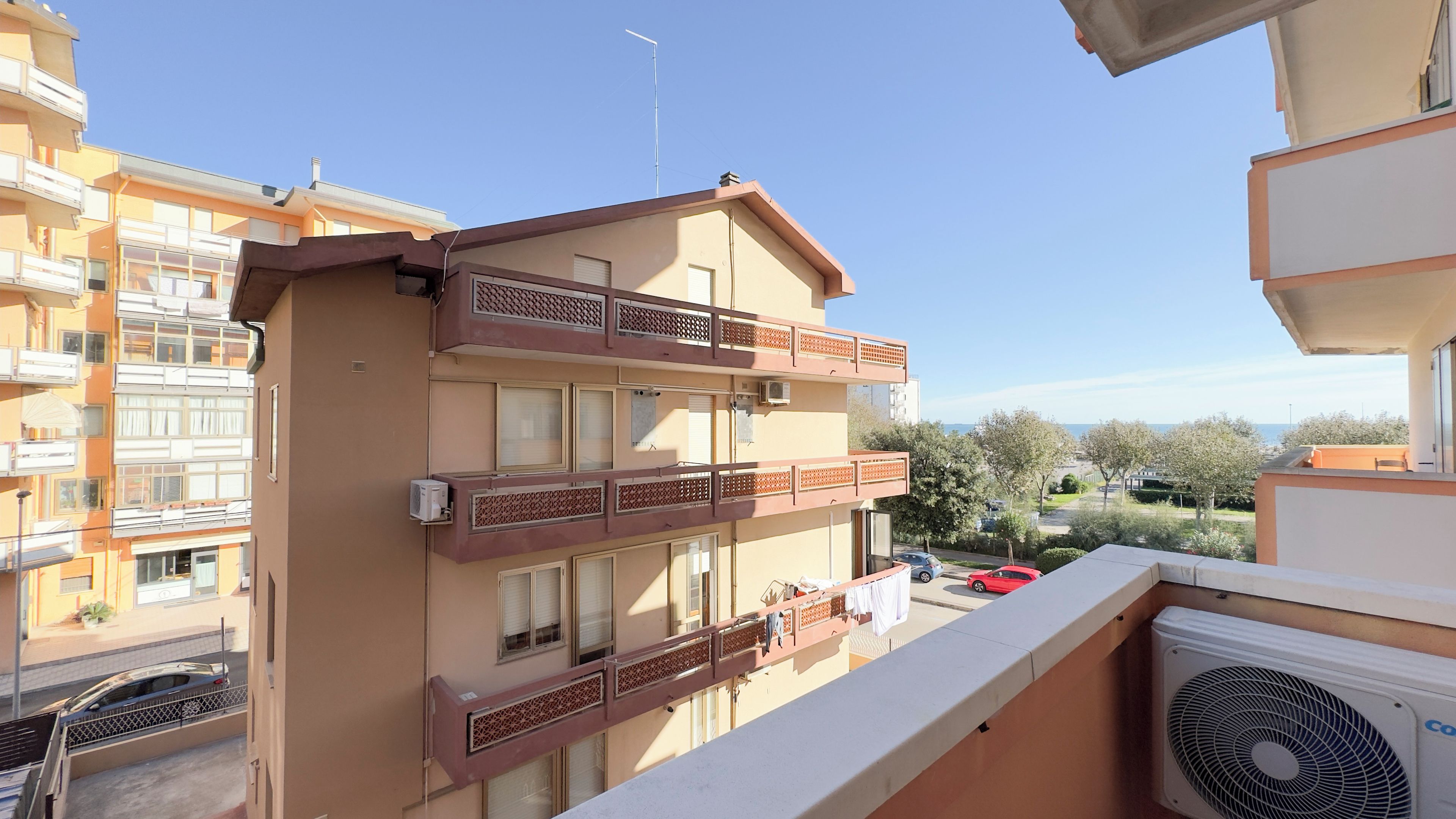 A multi-story residential building with balconies, air conditioning units, and a clear view of the surrounding neighborhood.