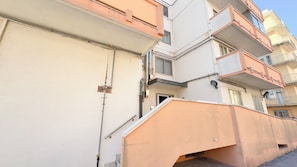 A multi-story residential building with balconies, a visible door, and a stairway leading to the entrance. - Appartamento Madagascar by Ca-sa Check (Chioggia)