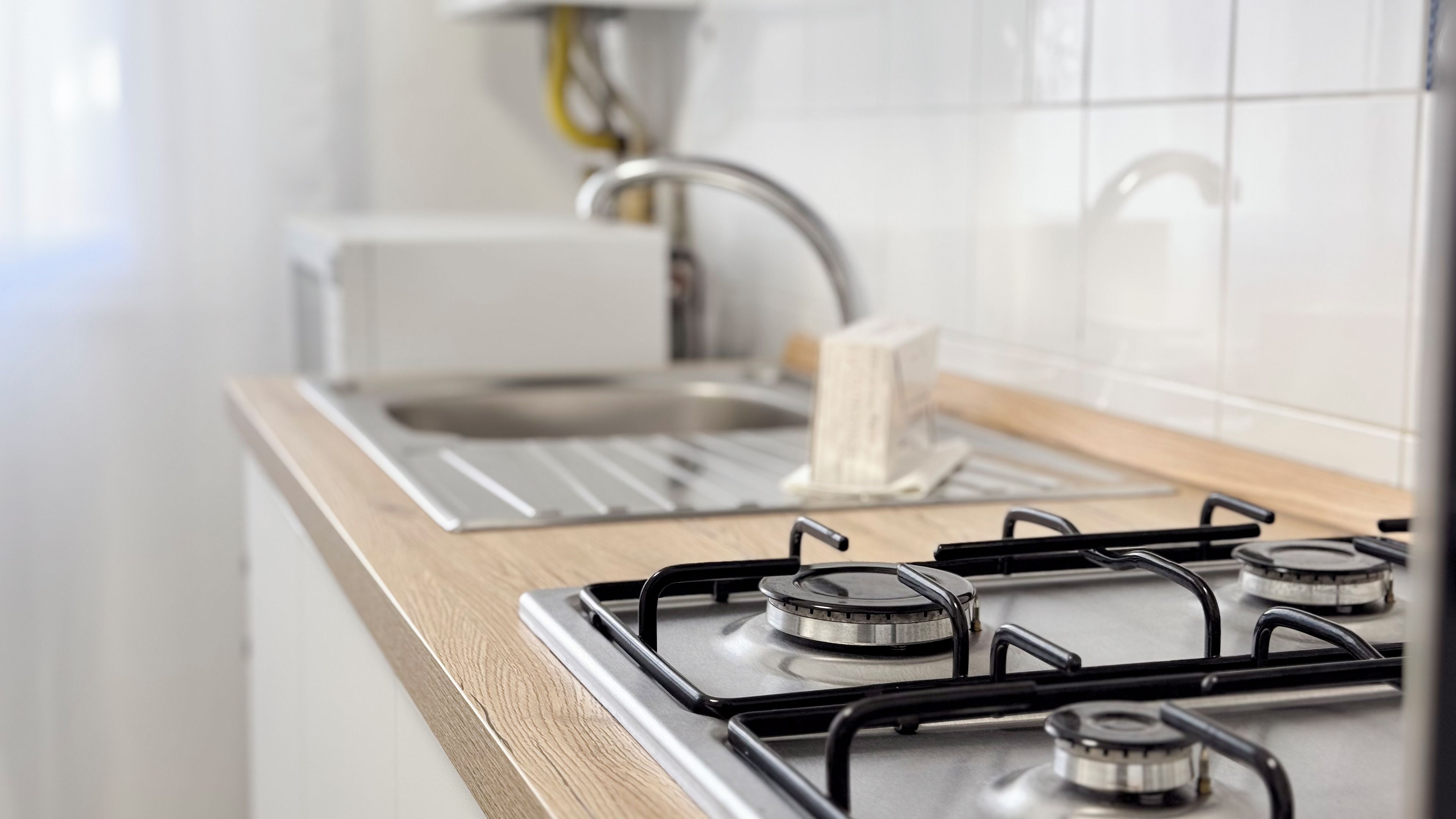 Een keuken met een gasfornuis, een spoelbak en een houten aanrecht.