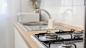 A kitchen with a gas stove, a sink, and a wooden countertop. - Appartamento Madagascar by Ca-sa Check (Chioggia)
