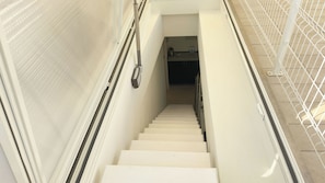Eine Treppe mit Handlauf, Lichtschalter und einer Metallgeländer an der rechten Seite.