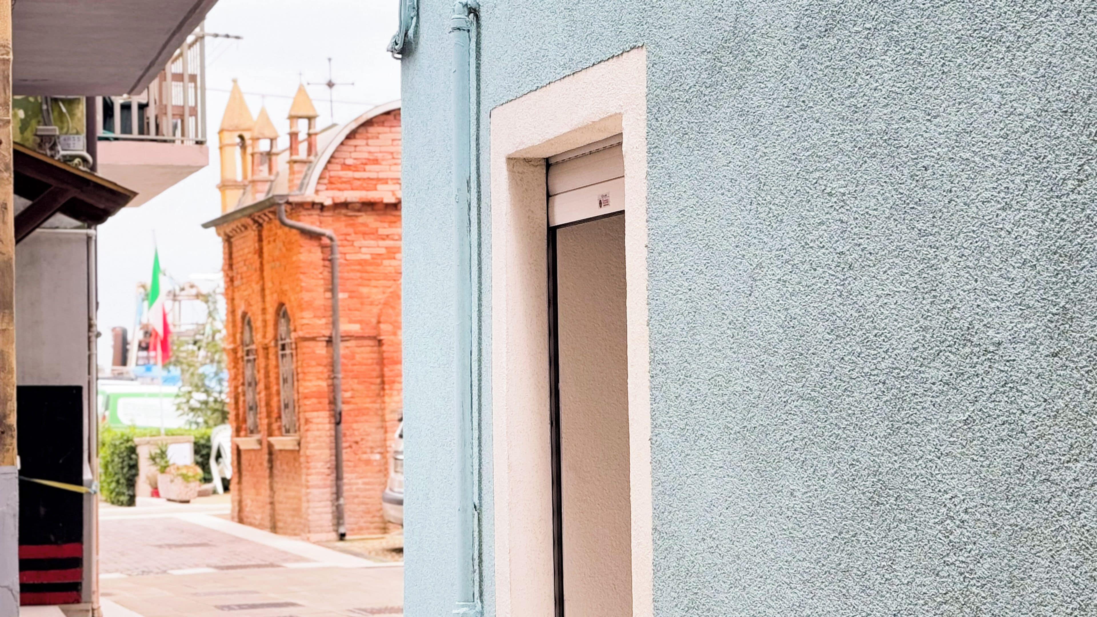 Une rue étroite bordée d’un immeuble à la façade en briques rouges et à la porte blanche.
