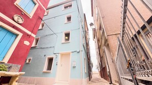 A narrow street with buildings featuring colorful facades and small windows. - Ca' Egle by Ca-sa Check (Chioggia)