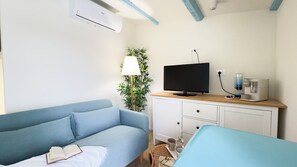 A room with a blue sofa, a television, a coffee machine, and a lamp. - Ca' Egle by Ca-sa Check (Chioggia)