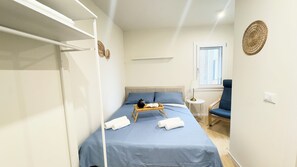 A bedroom with a bed, a chair, a bedside table, and a window. - Ca' Egle by Ca-sa Check (Chioggia)