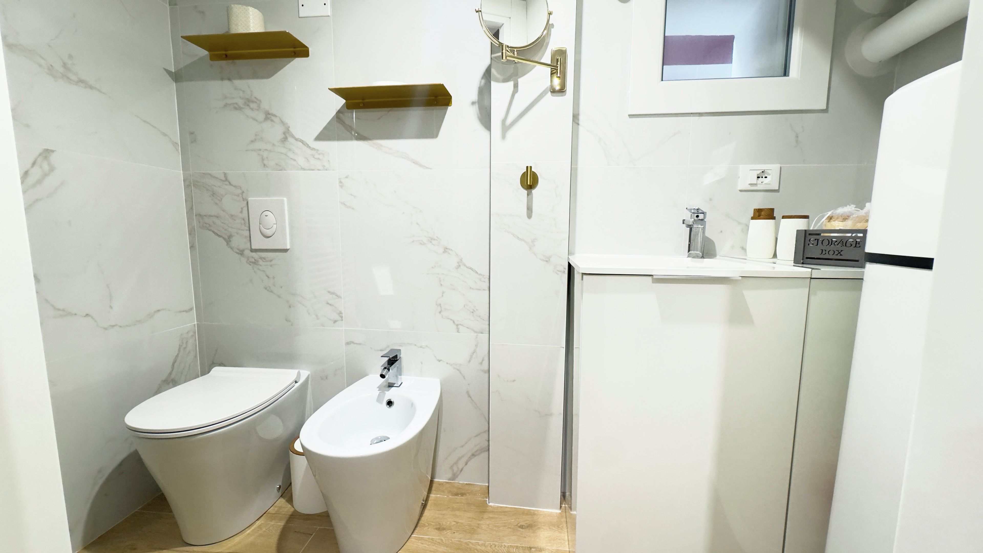 Ein modernes Badezimmer mit Toilette, Bidet und einem Waschtisch mit einer Aufbewahrungsbox.