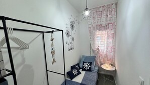 A small, cozy bedroom with a bed, a hanging light fixture, a wall decoration, and a patterned curtain. - Casa Angela by Ca-sa Check (Chioggia)