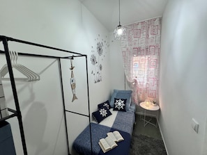 Un dormitori petit i acollidor amb un llit, una làmpada penjant, una decoració a la paret i una cortina amb dibuixos.