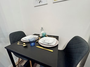Una mesa de comedor dispuesta con platos, cubiertos, un vaso azul y una botella de agua.