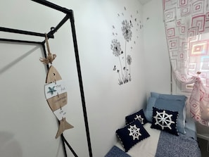 Un dormitorio con cama, almohadas, decoración en la pared y un adorno colgante.