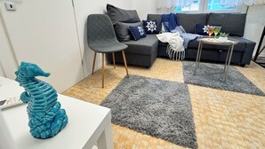 A modern living room with a grey sofa, a small table, a decorative seahorse, and a patterned rug. - Casa Angela by Ca-sa Check (Chioggia)