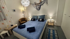A bedroom with a bed, a chair, a nightstand, a lamp, and a decorative hanging. - Casa Angela by Ca-sa Check (Chioggia)