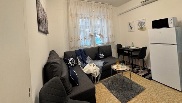 A compact living space with a sofa, a dining table, and a kitchenette. - Casa Angela by Ca-sa Check (Chioggia)