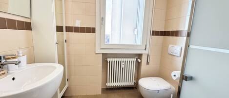 Un bagno con lavandino, WC e finestra.