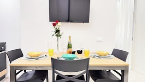 Mesa de jantar posta com vários recipientes, copos e uma garrafa de champanhe.