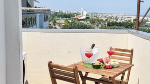 A wooden table with a bottle of champagne, two glasses, and a bowl of fruit on a balcony overlooking a cityscape. - Rooftop Blu Infinito by Ca-sa Check (Chioggia)