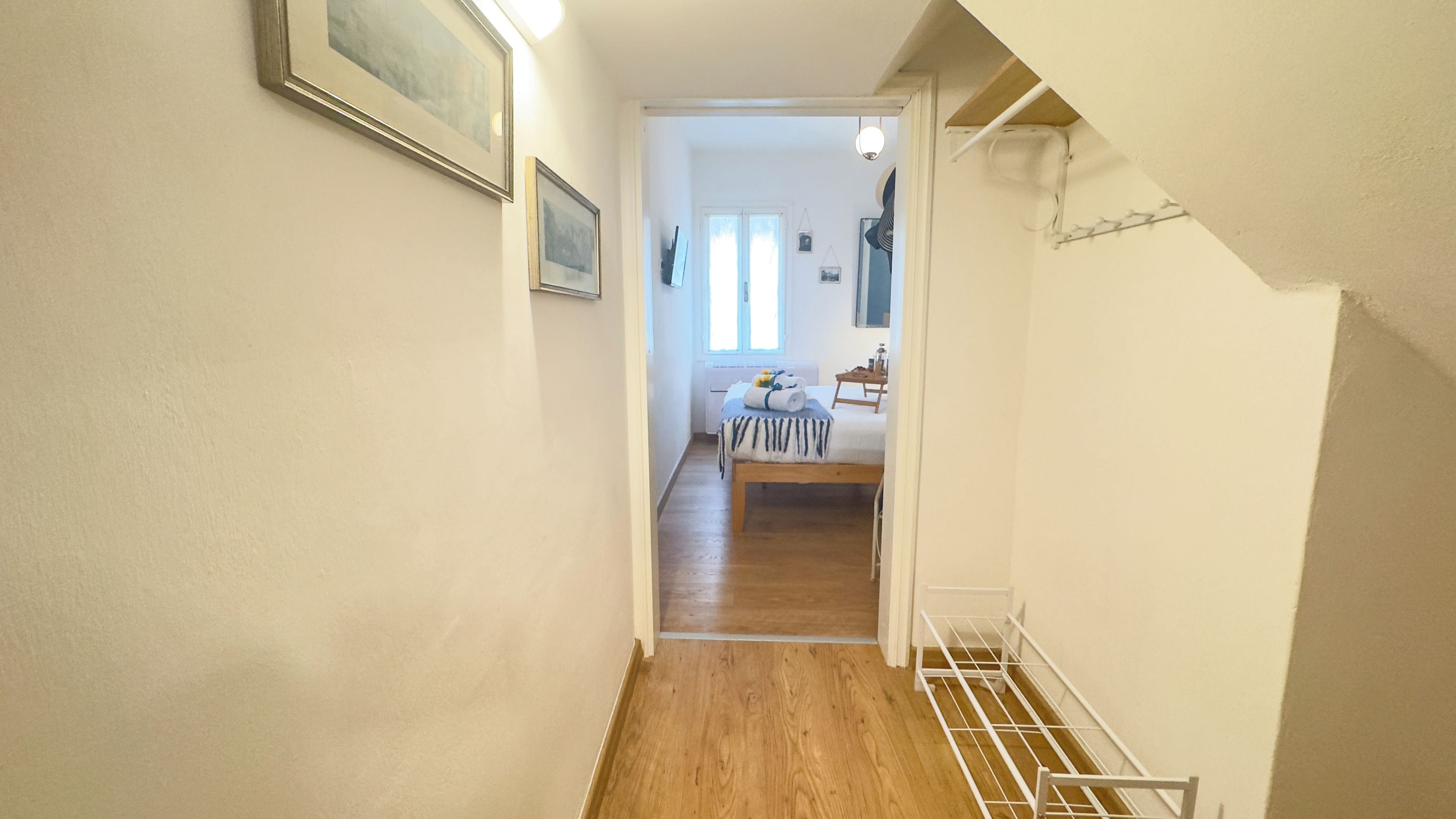 A narrow hallway with wooden flooring leading to a dining area with a table and chairs.