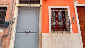 Un edificio con una puerta gris marcada con el número 589 y una ventana con barrotes.
