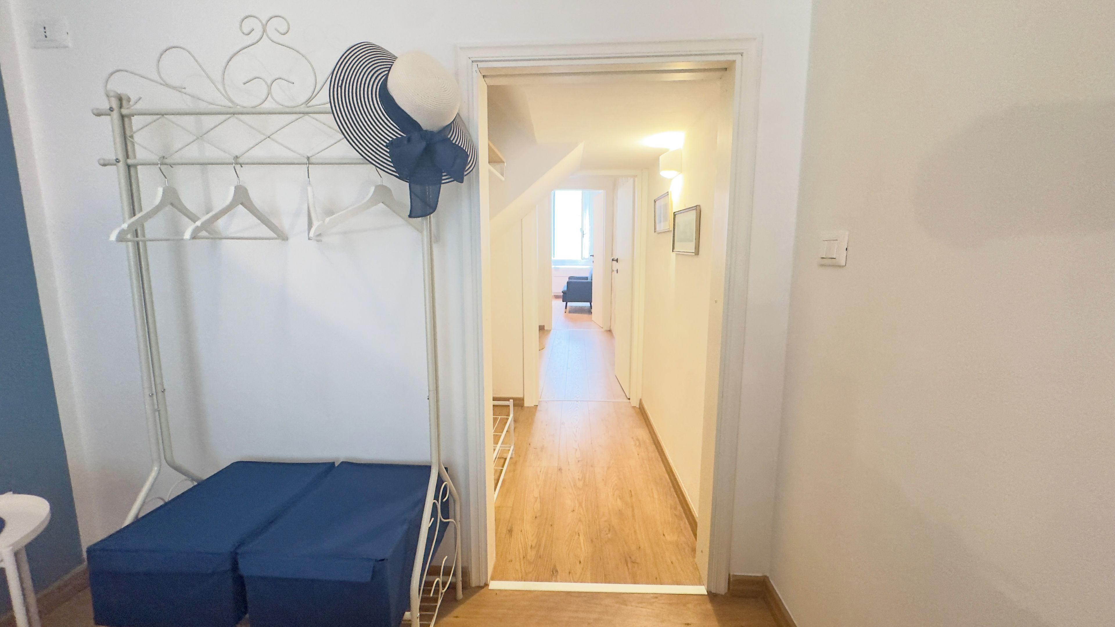 Una habitación con literas, un tendedero y un pasillo que da a otra habitación.