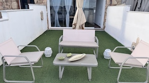 A patio with artificial grass, two cushioned chairs, a small table, and a white lantern. - La Casa Delle Stelle by Ca-sa Check (San Teodoro)
