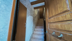 A wooden staircase leading to a room with a white wall and a wooden door. - Casa Andrea by Ca-sa Check (Chioggia)