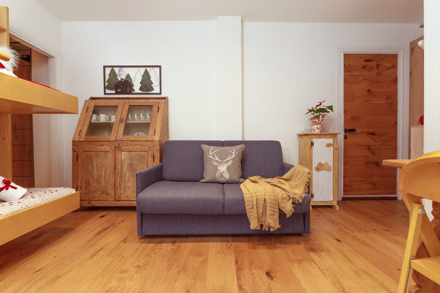 A cozy living room with a sofa, a wooden cabinet, and a door.