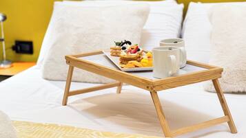Una cama con una bandeja de comida y dos tazas sobre un atril de madera.