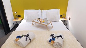 A hotel room with a bed, two nightstands, a bedside table with a lamp, and a tray with desserts and two mugs. - Tema Apartment by Ca-sa Check (Chioggia)