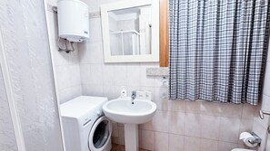 Un baño con lavadora, lavabo e inodoro.