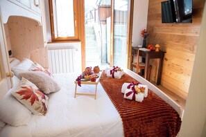 A cozy bedroom with a bed, a small table with a tray of food, and a wooden wall with a TV. - Appartamento Neve by Ca-sa Check (Aprica)