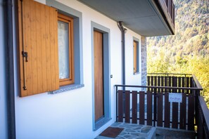 A building with wooden doors and windows, a stone staircase, and a wooden fence. - Appartamento Neve by Ca-sa Check (Aprica)