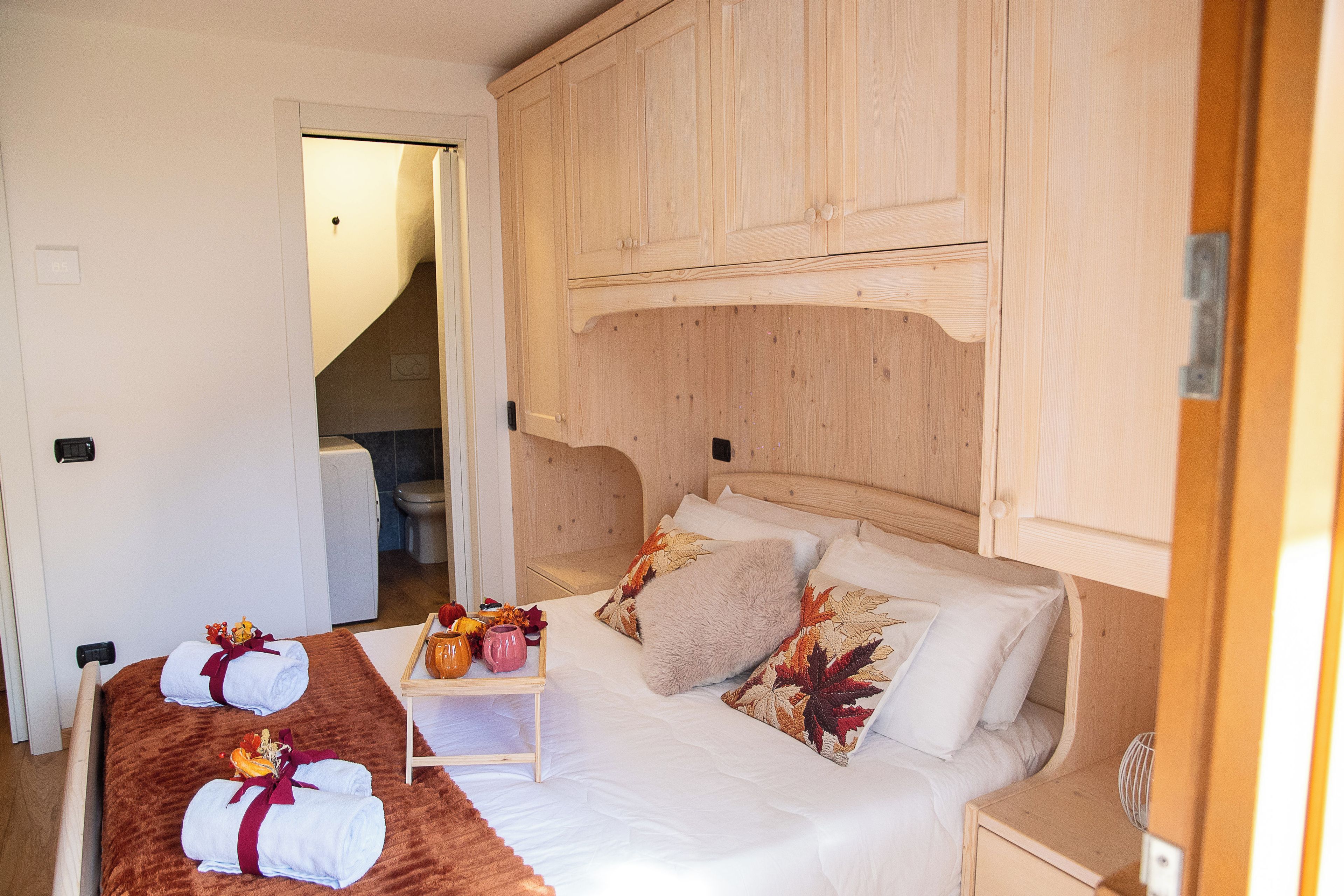 Ein Schlafzimmer mit einem Bett, Kissen, einem Nachttisch und einem Holzschrank.