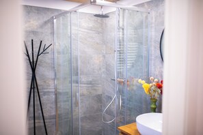 A modern bathroom with a glass-enclosed shower, a wooden vanity, and a vase of flowers. - Appartamento Neve by Ca-sa Check (Aprica)